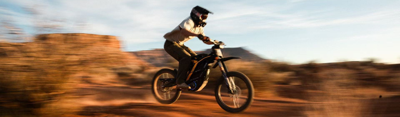 Piloto saltando com uma moto elétrica 79BIKE em terreno de terra